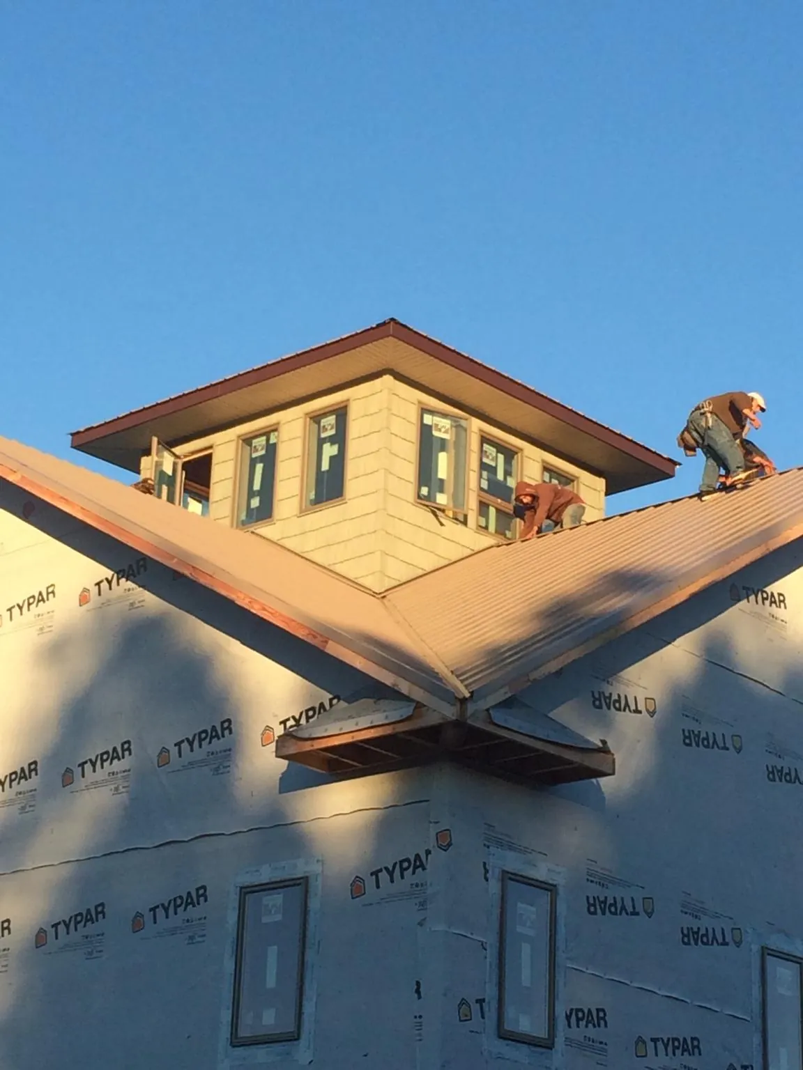 Roofers working around a rooftop cupola on a new metal roof at sunset — Roof Waterproofing in Round Mountain by Roofing Brothers